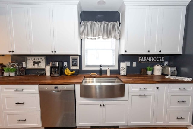 kitchen with butcher block countertops, white cabinets, a sink, and stainless steel dishwasher