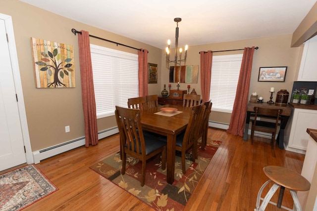 dining room featuring an inviting chandelier, a baseboard heating unit, and light wood-style floors