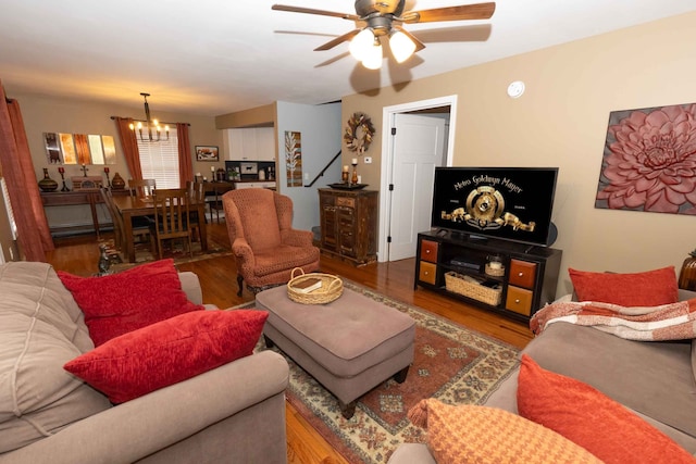 living area with wood finished floors and ceiling fan with notable chandelier