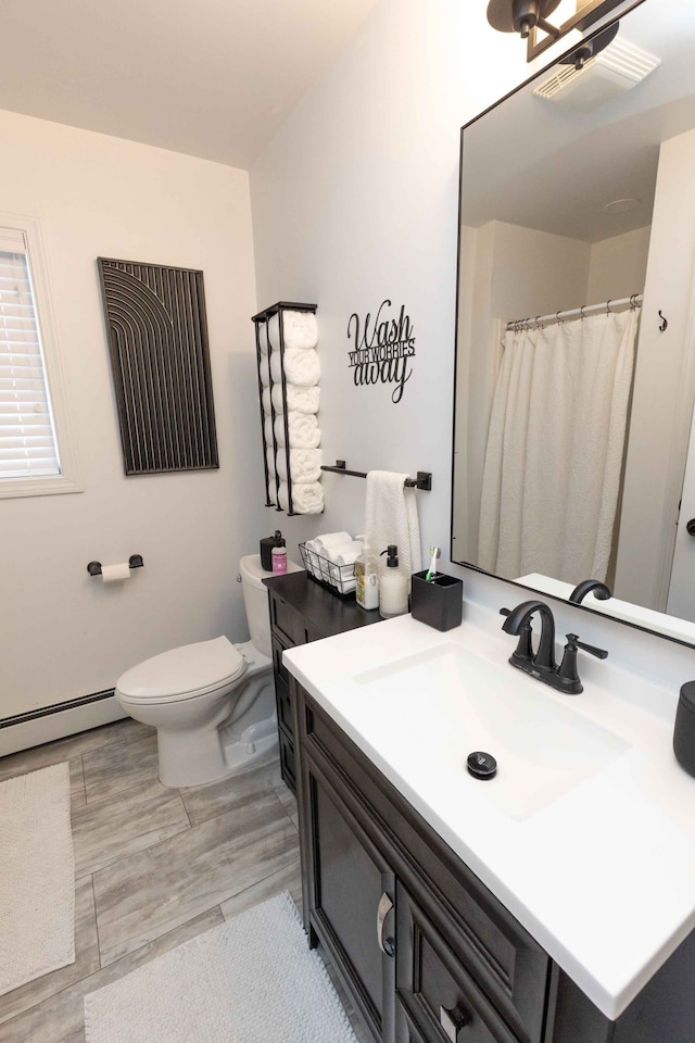 bathroom with vanity, wood finished floors, visible vents, a baseboard radiator, and toilet