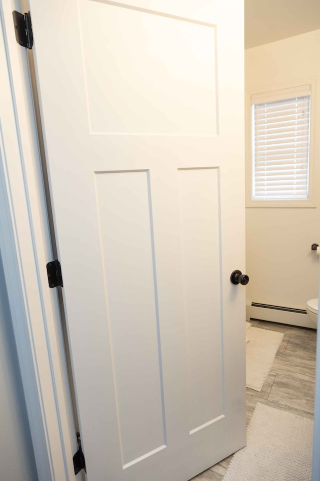 interior space with toilet and a baseboard heating unit