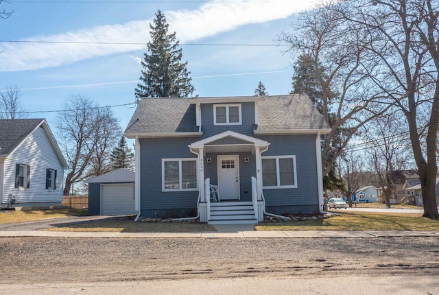 bungalow-style house with a garage, an outbuilding, and roof with shingles