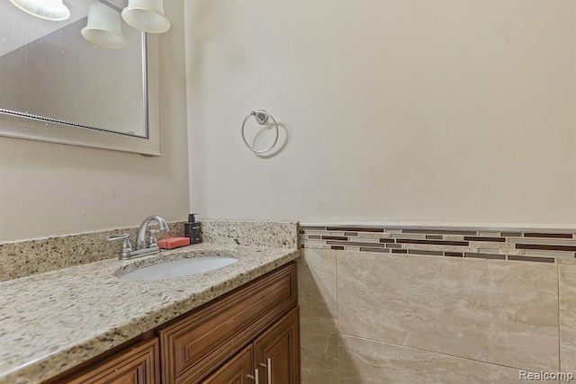 bathroom with a wainscoted wall, vanity, and tile walls