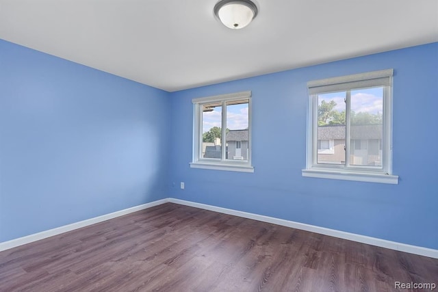 unfurnished room featuring dark wood-type flooring and baseboards