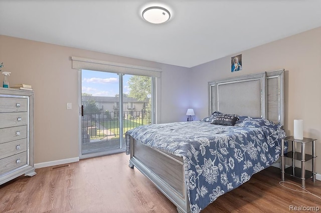 bedroom with access to exterior, visible vents, baseboards, and wood finished floors