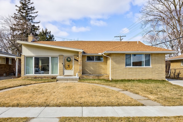 single story home featuring brick siding, a chimney, and a front yard