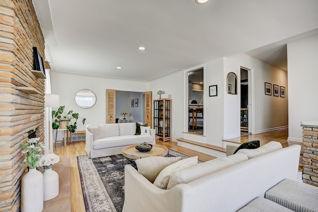 living room with light wood-style flooring, a fireplace, baseboards, and recessed lighting