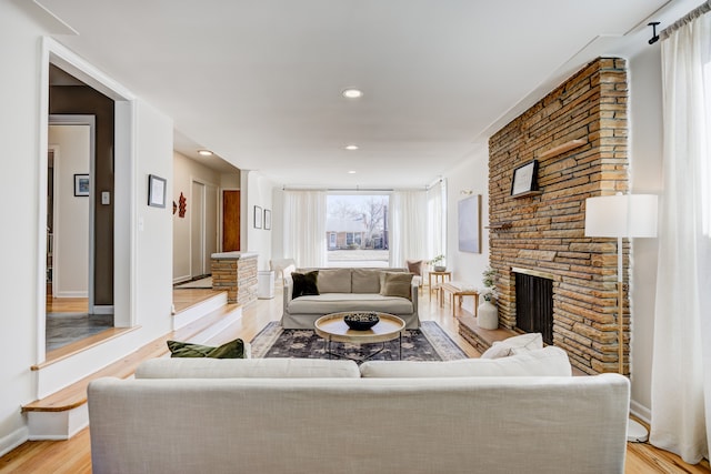 living room with baseboards, a stone fireplace, recessed lighting, and light wood-style floors