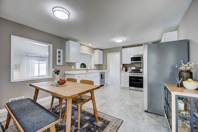 kitchen with light countertops, visible vents, appliances with stainless steel finishes, white cabinets, and a sink