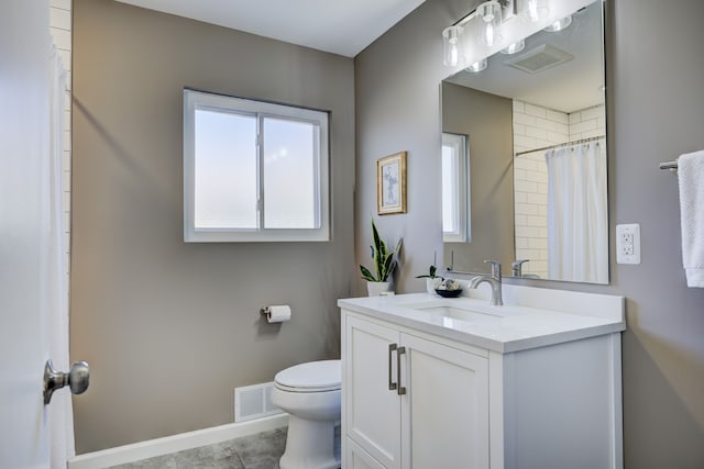 bathroom with toilet, vanity, visible vents, and baseboards