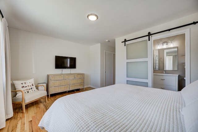 bedroom featuring a closet, light wood finished floors, and a barn door