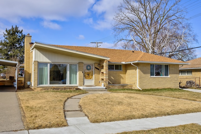 view of front facade with roof with shingles, a chimney, a front lawn, and brick siding