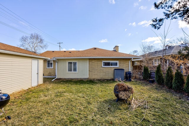 back of house with roof with shingles, brick siding, a yard, a chimney, and fence