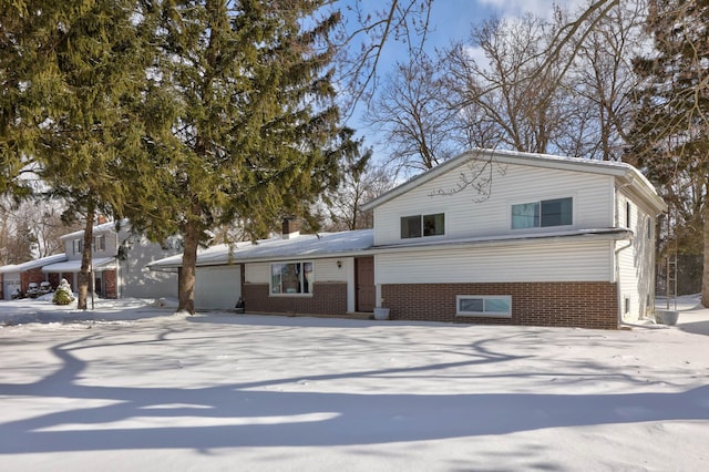 tri-level home featuring an attached garage and brick siding