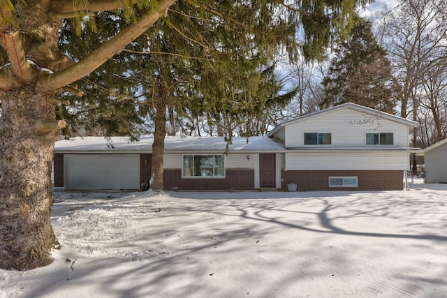 split level home featuring a garage, brick siding, and driveway