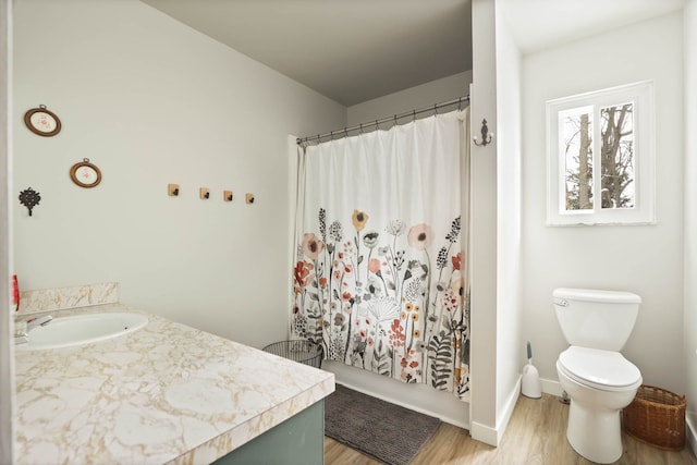 full bath with baseboards, a shower with shower curtain, toilet, wood finished floors, and vanity