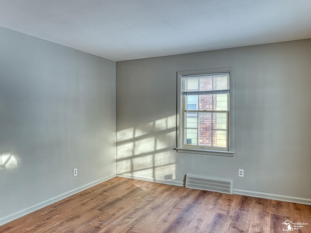 empty room featuring baseboards, visible vents, and wood finished floors