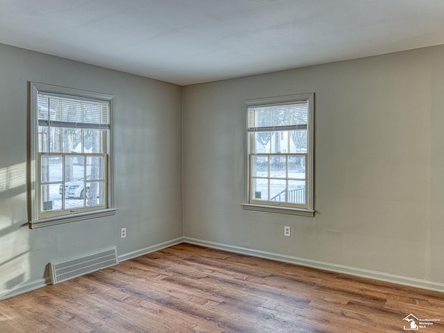 unfurnished room with visible vents, baseboards, and wood finished floors