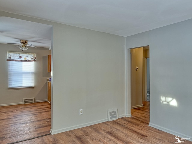 empty room with a ceiling fan, baseboards, visible vents, and light wood finished floors