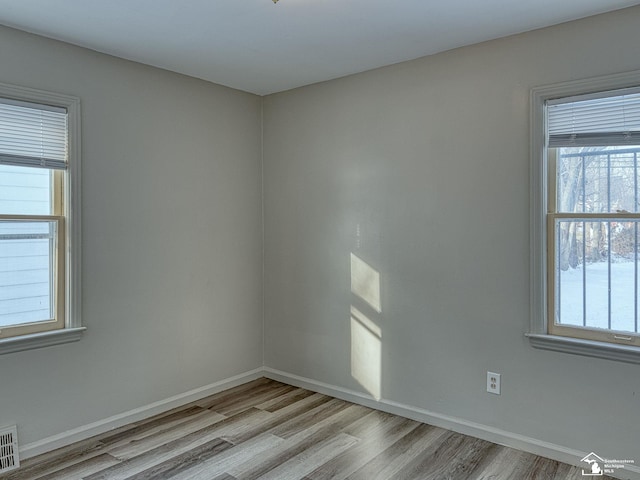 empty room featuring light wood-style flooring, visible vents, and baseboards