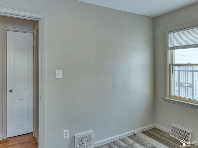 spare room with light wood-type flooring, visible vents, and baseboards