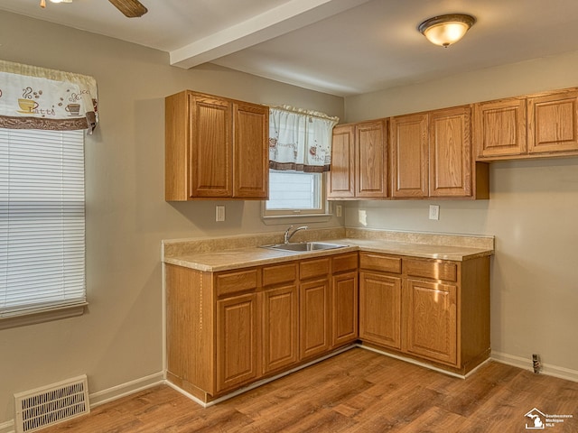 kitchen with light countertops, a sink, visible vents, and light wood-style floors