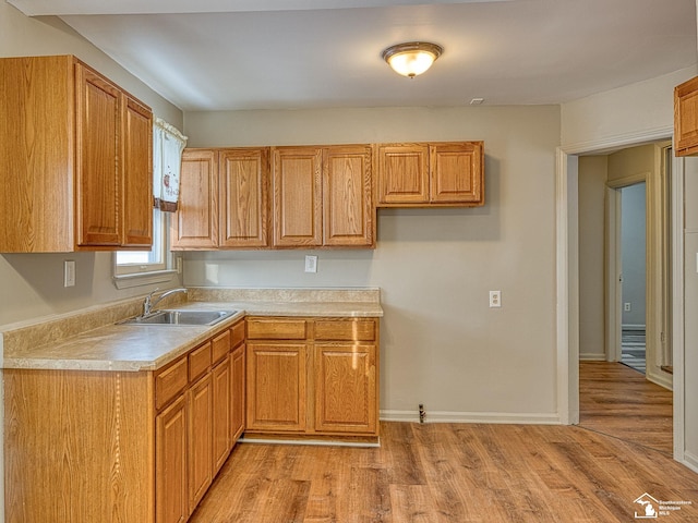 kitchen with brown cabinets, light wood-style floors, light countertops, and a sink