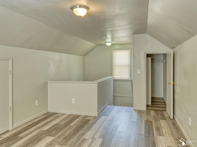 bonus room with lofted ceiling, light wood finished floors, and baseboards