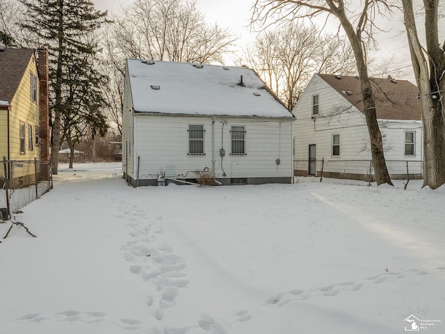 snow covered house featuring fence