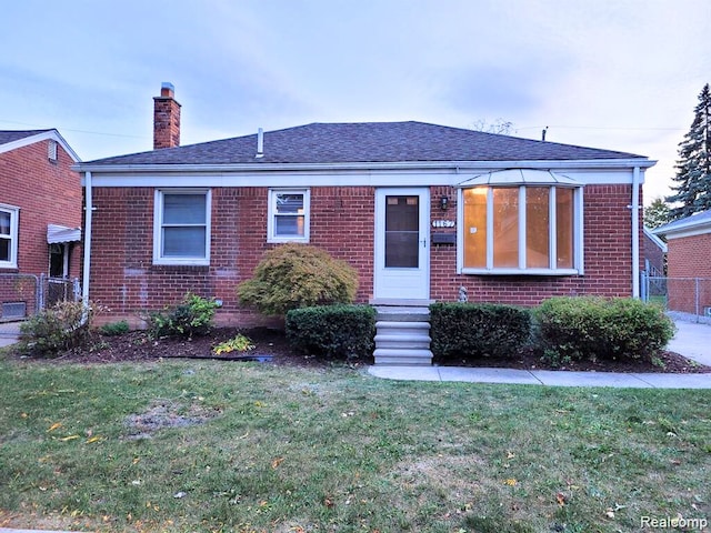 view of front facade with entry steps, brick siding, a chimney, and a front lawn