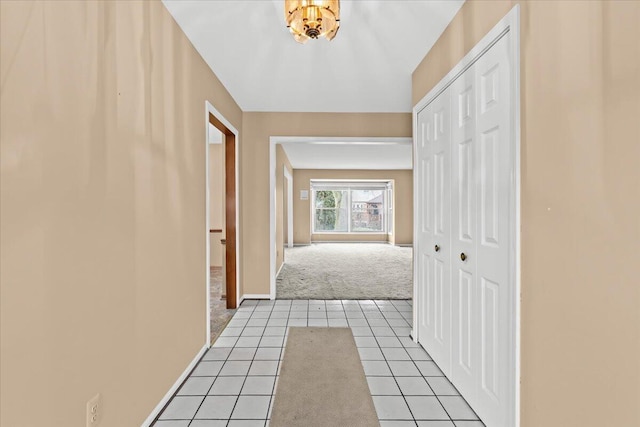 hall featuring baseboards, carpet flooring, and tile patterned floors