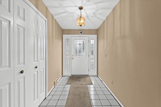 entryway featuring baseboards, a notable chandelier, and light tile patterned flooring