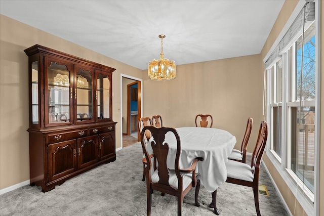 dining space featuring light carpet, a notable chandelier, and baseboards