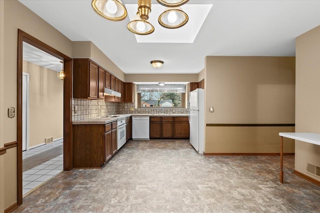 kitchen with tasteful backsplash, visible vents, white appliances, under cabinet range hood, and baseboards