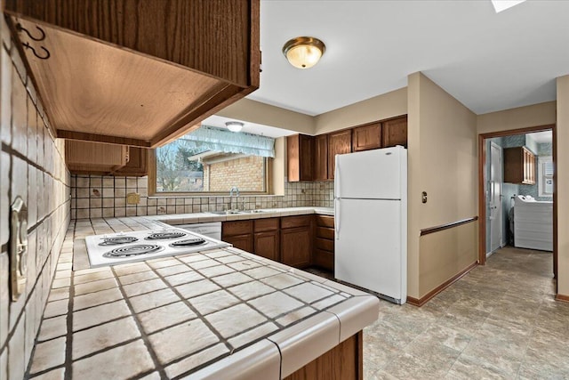 kitchen with tasteful backsplash, tile counters, stovetop, and freestanding refrigerator