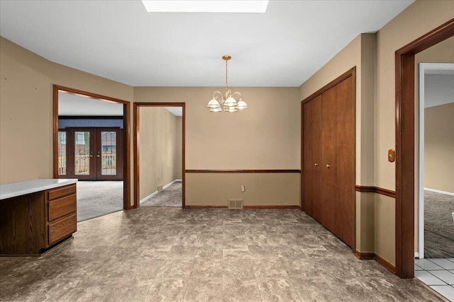 empty room with a chandelier, visible vents, baseboards, french doors, and carpet