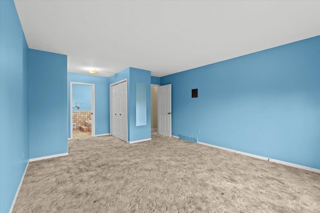 unfurnished bedroom with baseboards, visible vents, connected bathroom, carpet floors, and a closet