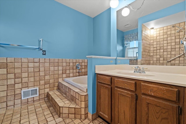 bathroom with a garden tub, vanity, visible vents, tile walls, and tile patterned floors