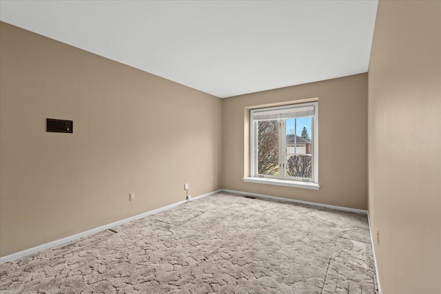 spare room featuring carpet, visible vents, and baseboards