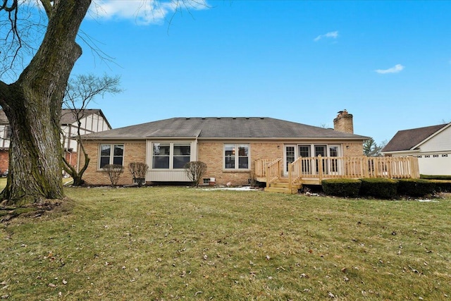 back of house featuring a chimney, a deck, a lawn, and brick siding