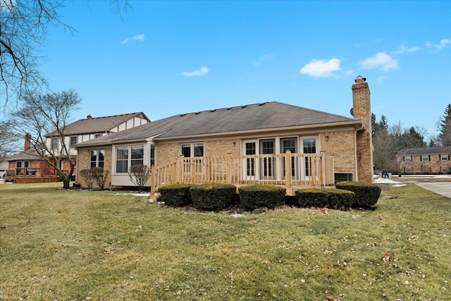 back of property featuring brick siding, a lawn, a chimney, and a wooden deck