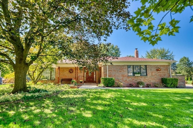 single story home with a chimney, a front lawn, and brick siding