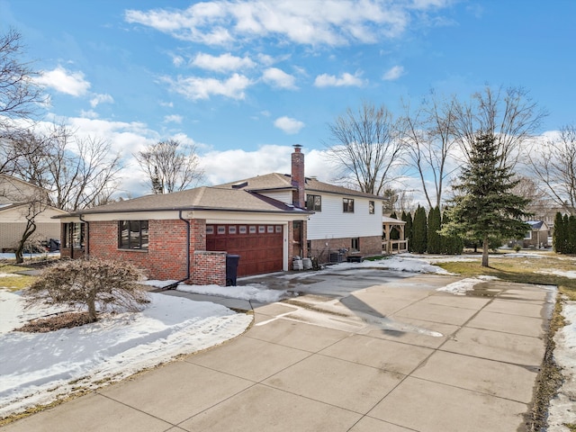 view of front of house with a garage, a chimney, concrete driveway, and brick siding