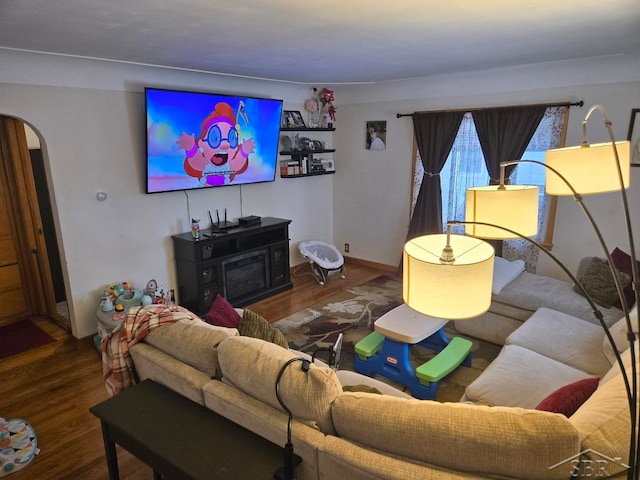 living area featuring arched walkways and wood finished floors