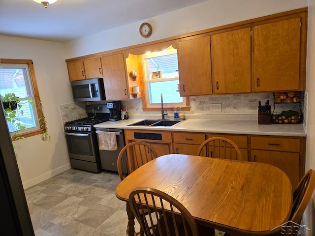 kitchen with appliances with stainless steel finishes, light countertops, a sink, and tasteful backsplash