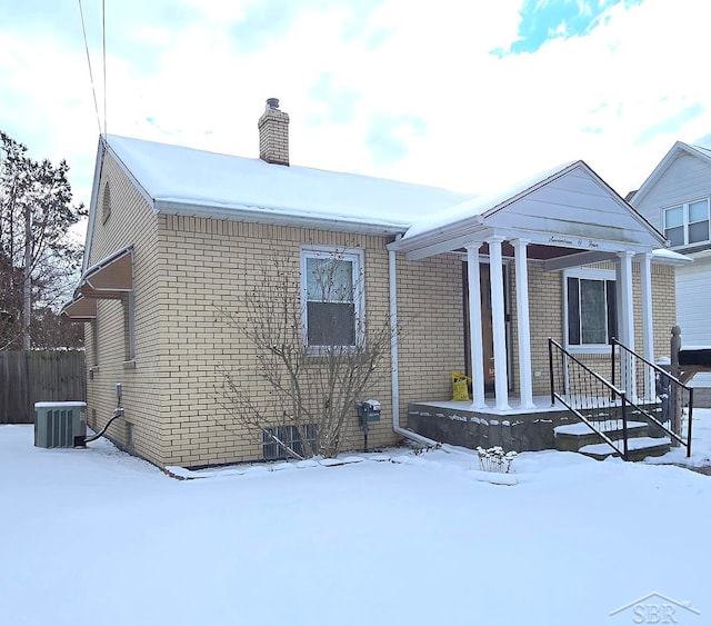 exterior space featuring brick siding, fence, a chimney, and central air condition unit