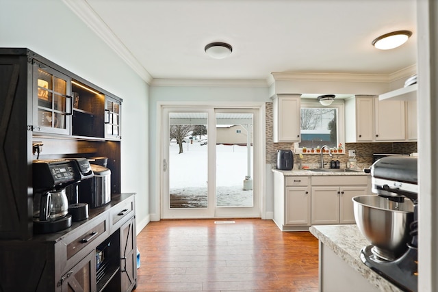 kitchen with ornamental molding, plenty of natural light, a sink, and light wood-style flooring