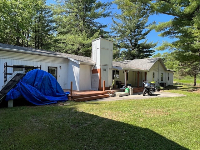 755 S M65 Rd, Twining, MI 48766 - back of property featuring a chimney, a yard, a patio, a wooden deck, and a shingled roof