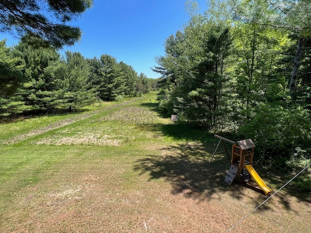 view of yard with a playground and a wooded view