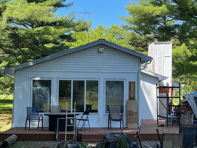 back of house with a chimney and a deck